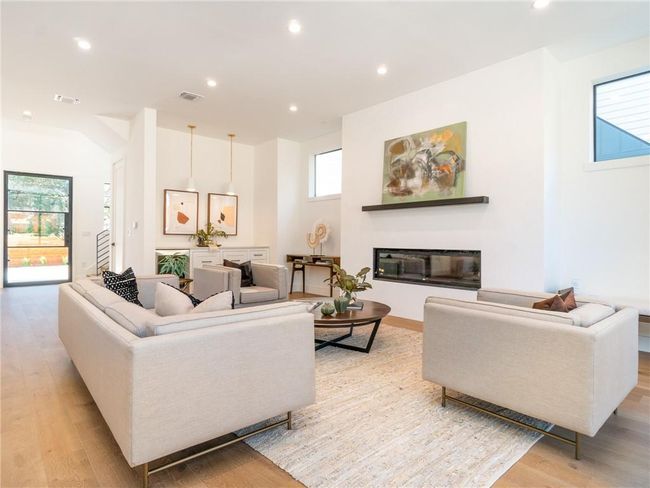 Living area featuring light wood-style flooring, recessed lighting, and a glass covered fireplace | Image 6