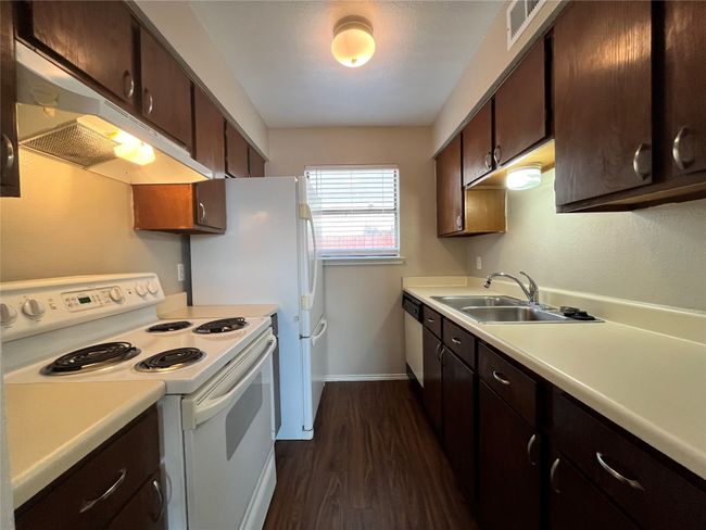 Here is the kitchen. Notice the stainless steel sink and white appliances. | Image 5