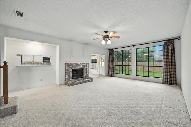 Unfurnished living room with ceiling fan, carpet flooring, a brick fireplace, and a textured ceiling | Image 11