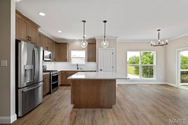 Kitchen with appliances with stainless steel finishes, a sink, light countertops, light wood-style floors, and a center island | Image 11