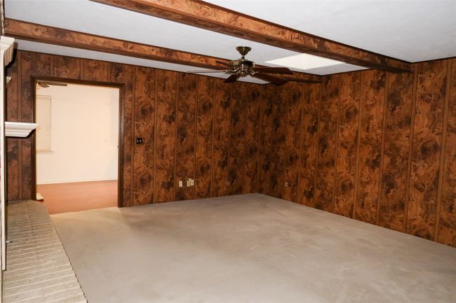 Carpeted spare room featuring wood walls, beamed ceiling, and ceiling fan | Image 21