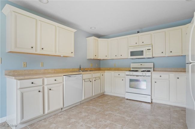Kitchen with white appliances, light countertops, recessed lighting, and a sink | Image 18