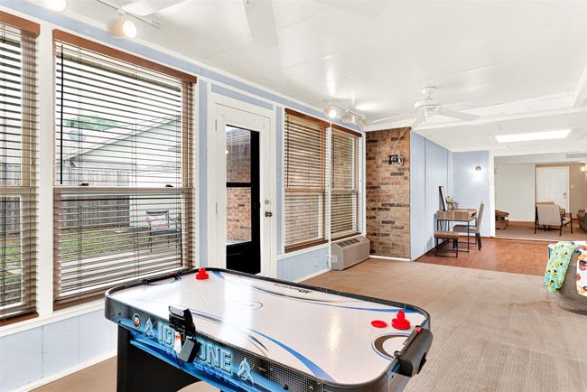 Recreation room with ceiling fan, wood finished floors, and brick wall | Image 13