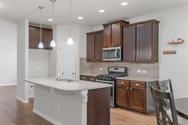 Kitchen with backsplash, light wood-style flooring, a sink, and stainless steel appliances | Image 18