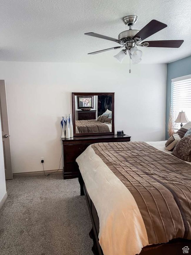 Carpeted bedroom featuring a textured ceiling, a ceiling fan, and baseboards | Image 9