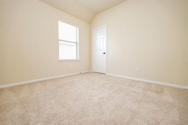 A corner window in a carpeted secondary bedroom offers more wall/floor space for furnishings. | Image 20