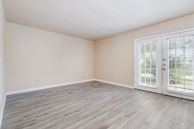 Empty room with light wood-style floors and french doors | Image 8