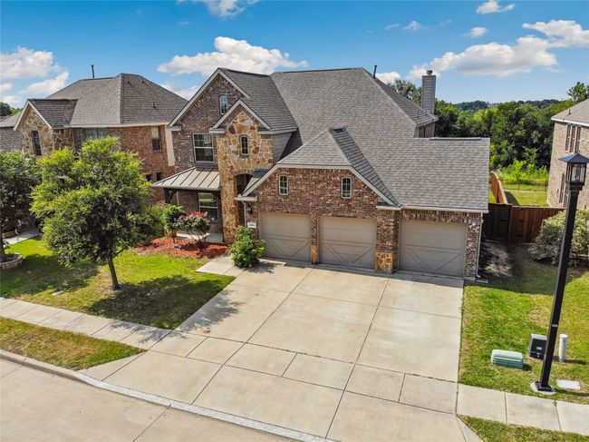 View of front of property with concrete driveway, a chimney, roof with shingles, brick siding, and a garage | Image 36