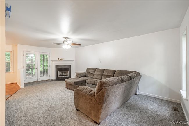Living room featuring carpet flooring, a ceiling fan, and a fireplace with flush hearth | Image 10