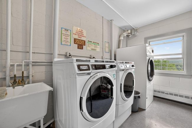Shared laundry room featuring separate washer and dryer, concrete block wall, and a baseboard radiator | Image 37