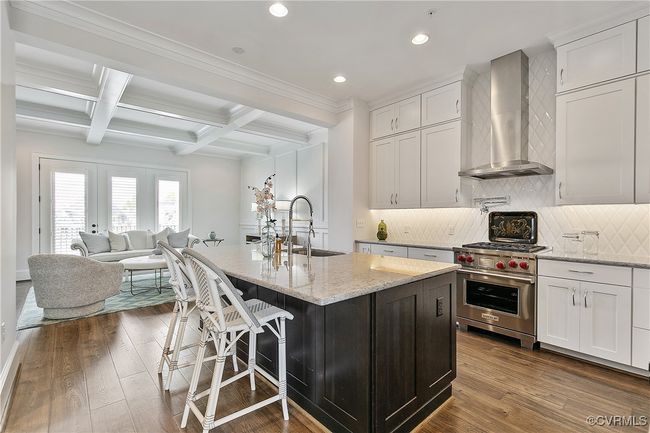 Kitchen with light stone counters, open floor plan, white cabinets, premium range, and wall chimney exhaust hood | Image 6