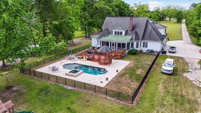 Rear view of house featuring a deck, a chimney, a pool with connected hot tub, a patio, and central air condition unit | Image 25