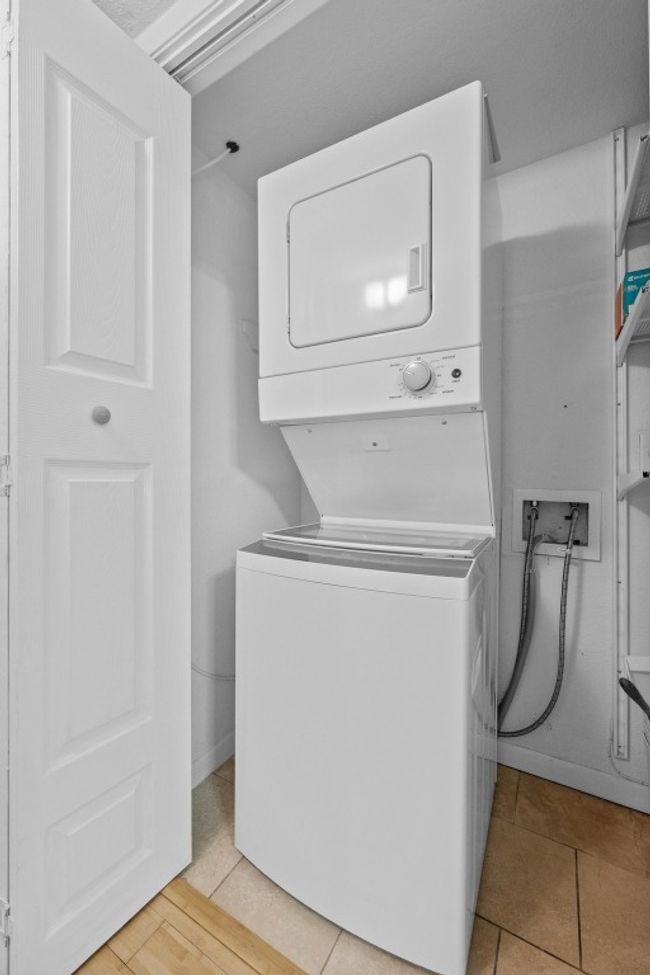 Laundry room featuring stacked washer / drying machine and light tile patterned flooring | Image 13