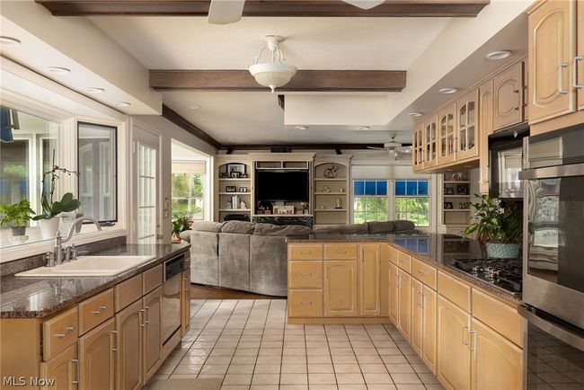 Kitchen featuring black gas cooktop, beam ceiling, sink, light tile flooring, and ceiling fan | Image 26