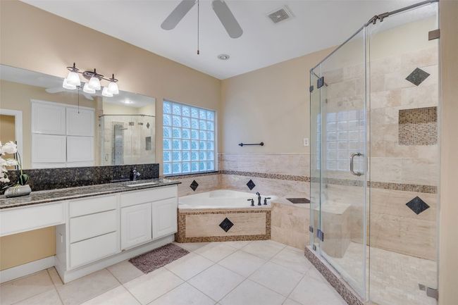 Bathroom with a garden tub, ceiling fan, vanity, tile patterned floors, and a shower stall | Image 25