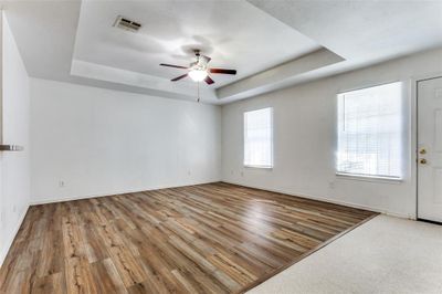 Unfurnished room with light hardwood / wood-style floors, ceiling fan, and a tray ceiling | Image 3