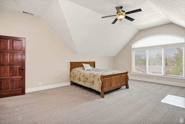 Bedroom featuring light colored carpet, lofted ceiling, and ceiling fan | Image 52