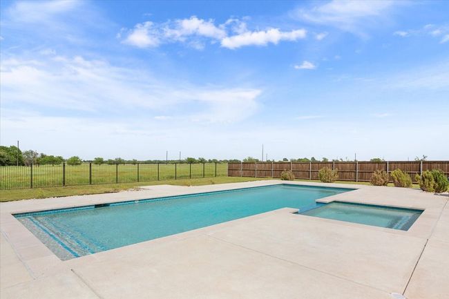 View of swimming pool featuring a fenced backyard, a patio area, and a pool with connected hot tub | Image 38