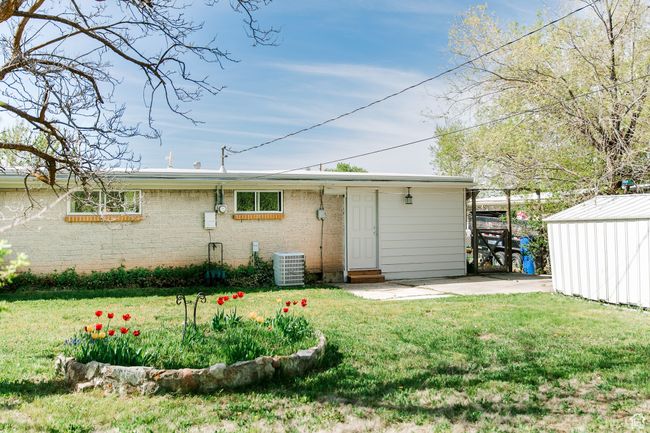 Rear view of property featuring an outdoor structure, a patio area, central air condition unit, and a lawn | Image 25