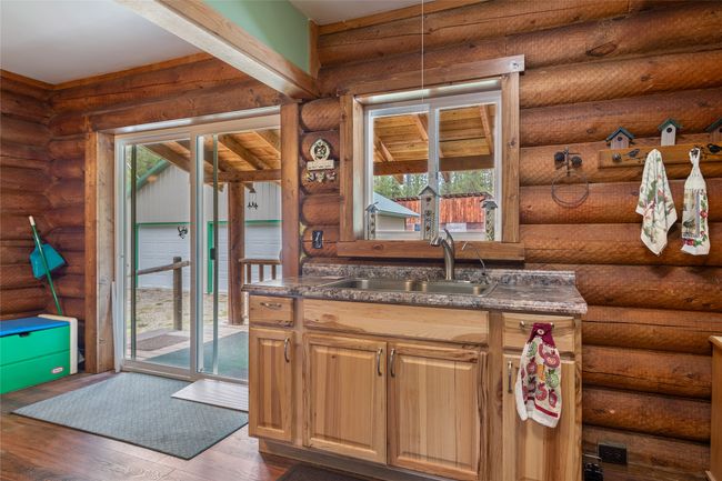 Kitchen featuring healthy amount of natural light, dark countertops, dark wood finished floors, rustic walls, and decorative light fixtures | Image 42