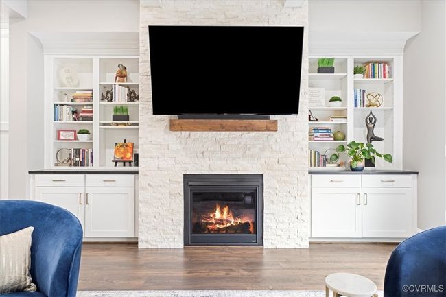 Living area featuring wood finished floors, a fireplace, and built in shelves | Image 12