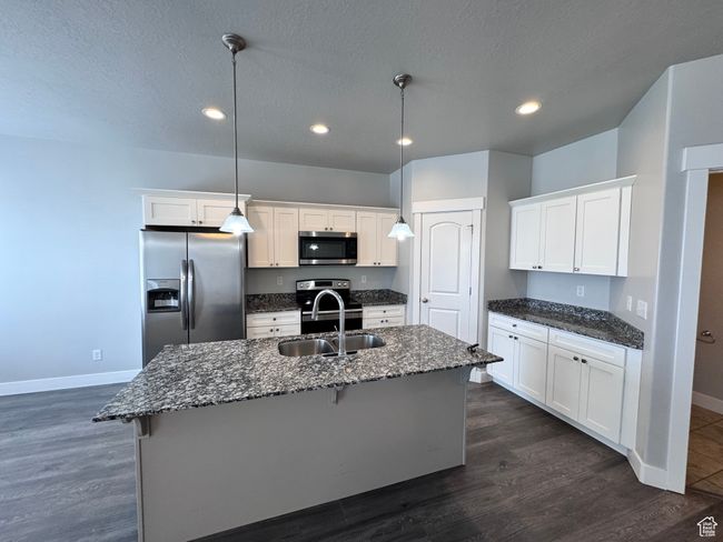 Kitchen featuring white cabinetry, a breakfast bar area, appliances with stainless steel finishes, a sink, and baseboards | Image 7
