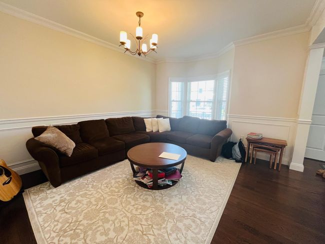Living room featuring ornamental molding, a chandelier, dark wood finished floors, a wainscoted wall, and a decorative wall | Image 8