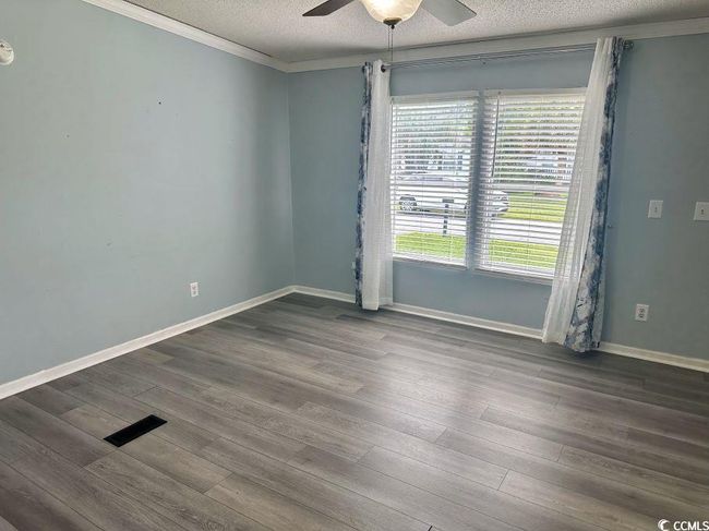 Empty room with ornamental molding, ceiling fan, a textured ceiling, wood finished floors, and baseboards | Image 12