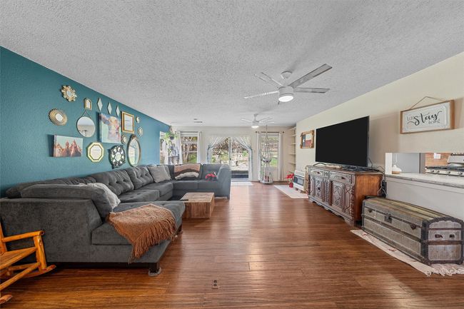 Living area with ceiling fan, wood finished floors, and a textured ceiling | Image 8