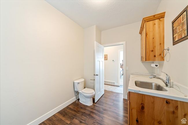 Clothes washing area featuring dark wood finished floors, baseboards, a sink, and visible vents | Image 36