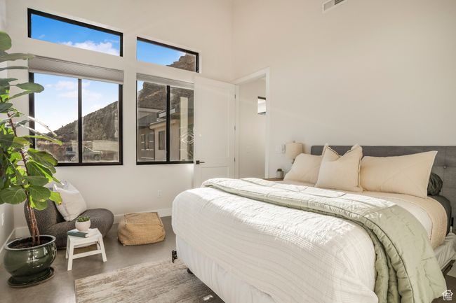 Bedroom with finished concrete floors, a towering ceiling, and baseboards | Image 36