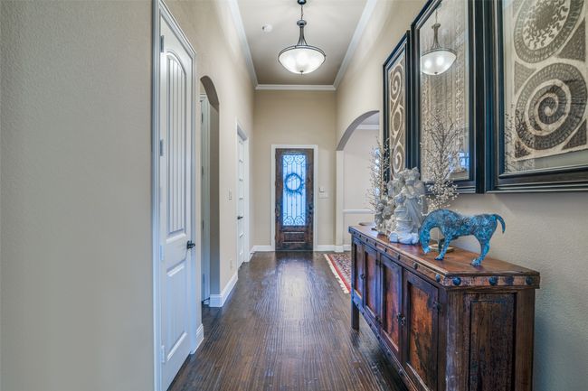 Entryway featuring baseboards, arched walkways, and crown molding. It leads to the living room, secondary bedrooms and the coat and a linen closet. | Image 5