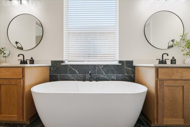 Bathroom with two vanities, a soaking tub, tile walls, and wainscoting | Image 24