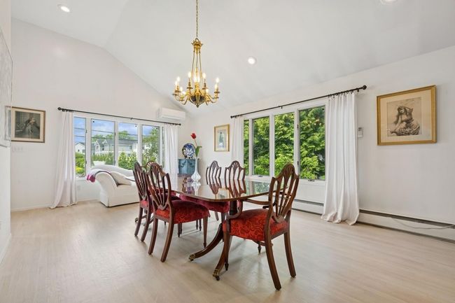 Dining area featuring a wall mounted air conditioner, a chandelier, light wood finished floors, high vaulted ceiling, and baseboard heating | Image 8