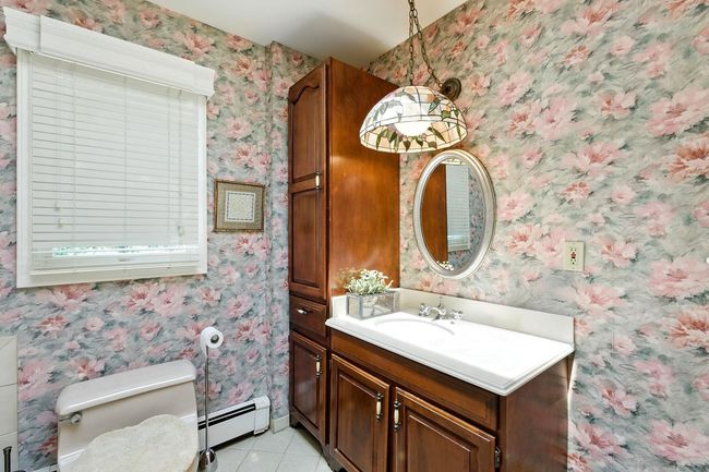 Bathroom with baseboard heating, tile patterned floors, vanity, and wallpapered walls | Image 21