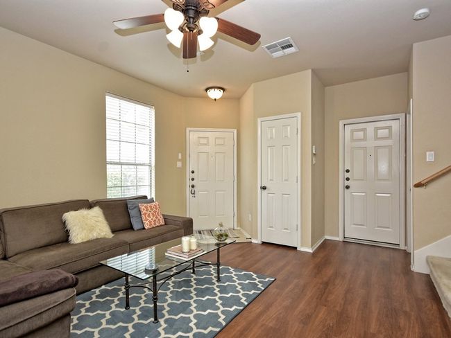 Living room with dark wood finished floors, baseboards, a ceiling fan, and stairway | Image 4