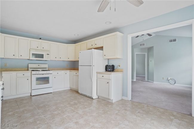 Kitchen with white appliances, light countertops, lofted ceiling, ceiling fan, and light carpet | Image 20