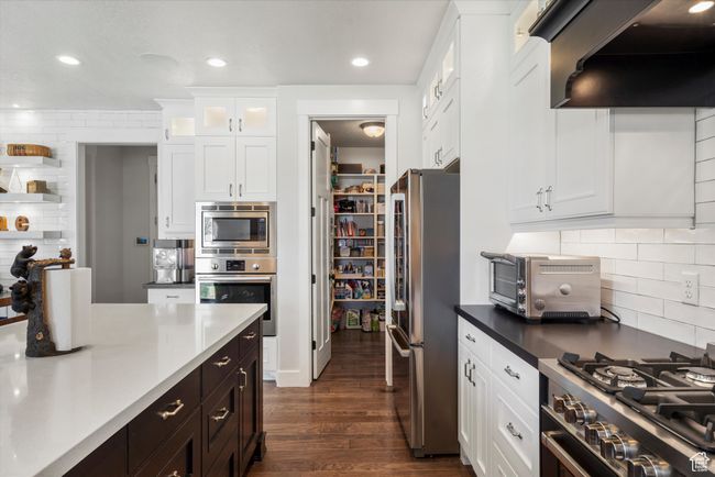 Kitchen featuring dark wood-style flooring, a toaster, white cabinets, stainless steel appliances, and ventilation hood | Image 19