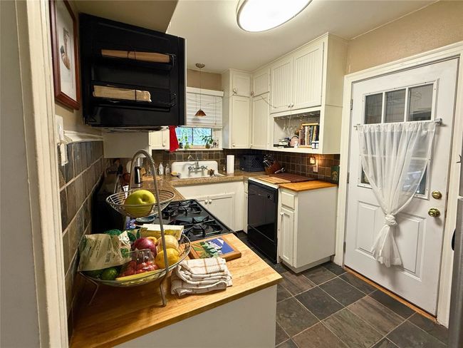 Kitchen with wood counters, dishwasher, decorative backsplash, and white cabinets | Image 7