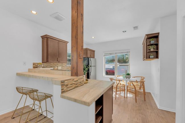 Kitchen featuring open shelves, freestanding refrigerator, decorative backsplash, recessed lighting, and a breakfast bar | Image 8