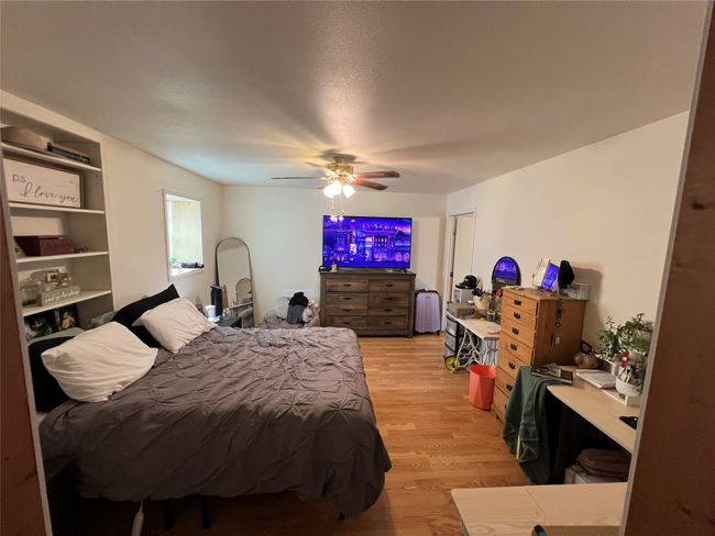 Bedroom with light wood finished floors, a ceiling fan, and radiator | Image 17