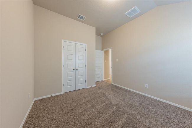 Unfurnished bedroom with carpet floors, vaulted ceiling, baseboards, and a closet | Image 16