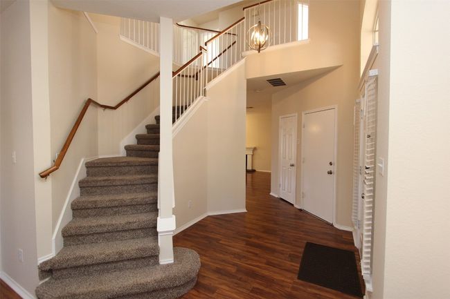 Foyer featuring wood finished floors, stairs, a high ceiling, and a chandelier | Image 9