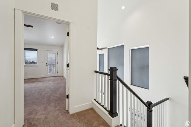 Hall with visible vents, an upstairs landing, baseboards, and carpet flooring | Image 41
