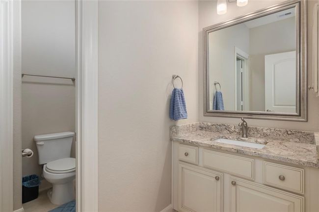 This photo shows a clean, modern bathroom with a granite countertop, under-mount sink, and large framed mirror. It features a separate toilet area and light neutral tones, creating a fresh and inviting space. | Image 37