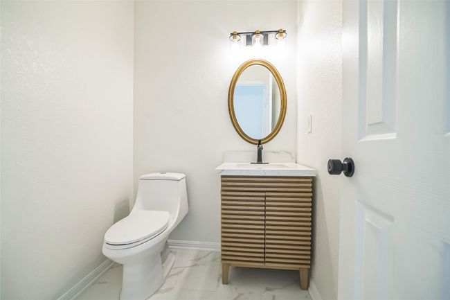 Half bath featuring marble finish flooring, vanity, toilet, and baseboards | Image 10
