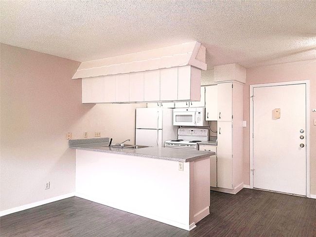 Kitchen with a breakfast bar and white appliances. | Image 7