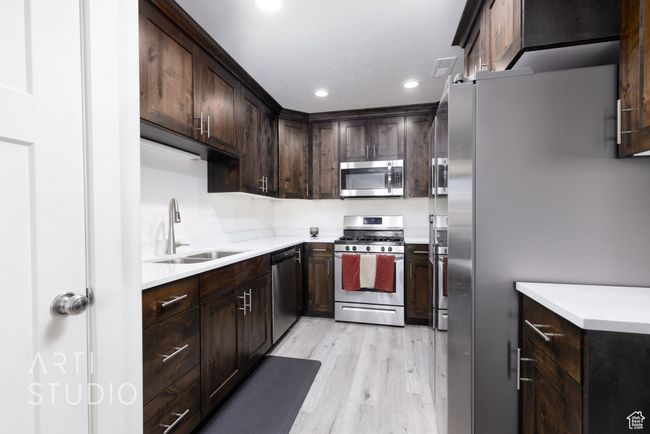 Kitchen featuring recessed lighting, dark brown cabinets, light wood-style floors, stainless steel appliances, and a sink | Image 13