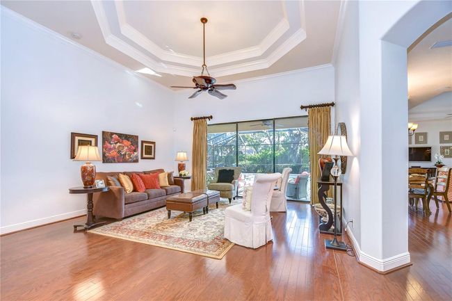 Bask in the natural light that floods this inviting formal living room, highlighted by elegant tray ceilings and gleaming hardwood floors. | Image 6