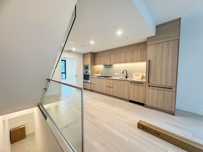Kitchen featuring dishwasher, light brown cabinets, a sink, modern cabinets, and light wood-type flooring | Image 36